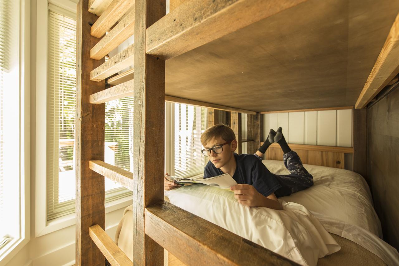 A young boy reading a magazine in the bottom bunk of the bunk bed set in the family room at the Ozark Folk Center State Park